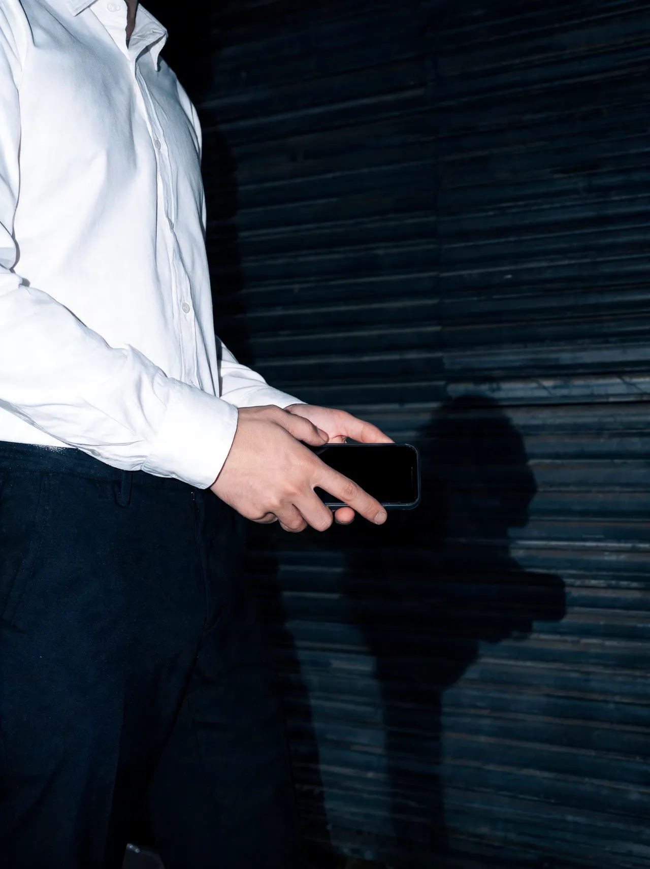 Hand mit Handy im Blitzlicht vor einem Rolltor